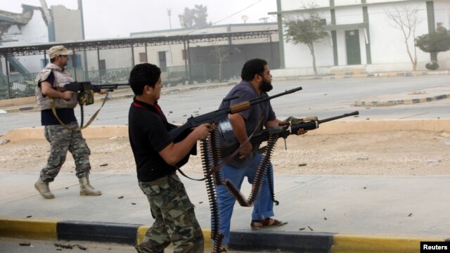 Militia fighters are seen shooting at a building in center of Bani Walid, Libya, October 24, 2012. 