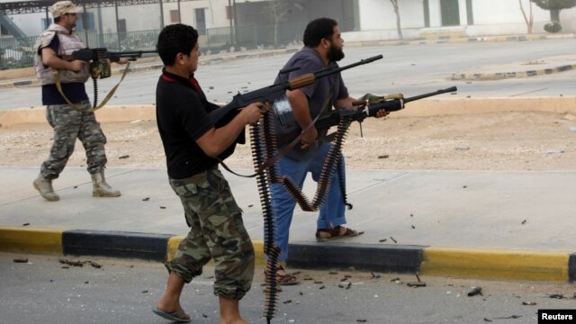 Militia fighters are seen shooting at a building in the center of Bani Walid, Libya, October 24, 2012.