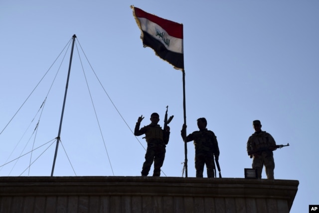 FILE - Iraqi soldiers plant the national flag over a government building in Ramadi as security forces advance their position in northern Ramadi, 115 kilometers (70 miles) west of Baghdad, Iraq, Dec. 21, 2015.
