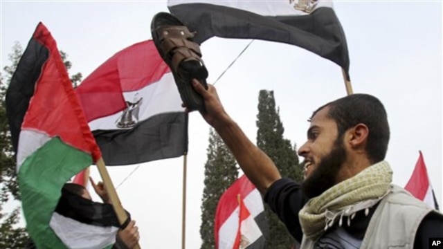 A Palestinian protester holds a shoe as others wave Palestinian and Egyptian flags during a demonstration calling for the removal of Egyptian President Hosni Mubarak in Gaza City, Feb 3, 2011