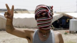 Penaberekî Kurd yê Sûrî li kampeke penaberan ya li bajarê Zaxoyê nîşana serkeftinê dike. Hezîran 23, 2012. 