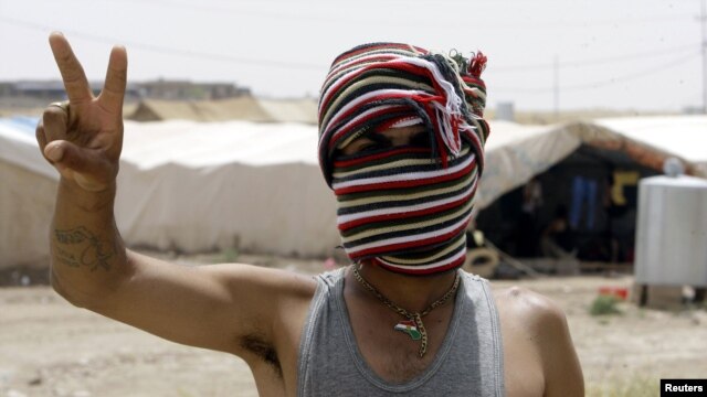 Penaberekî Kurd yê Sûrî li kampeke penaberan ya li bajarê Zaxoyê nîşana serkeftinê dike. Hezîran 23, 2012. 