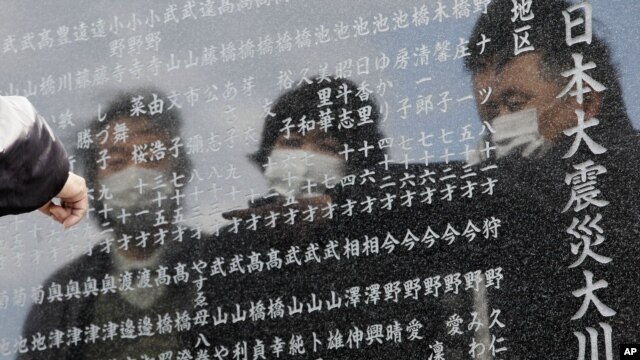 A man points to the name of one of the victims of the earthquake and tsunami inscribed in a cenotaph in Okawa district in Ishinomaki, Miyagi Prefecture, northern Japan, March 11, 2013.