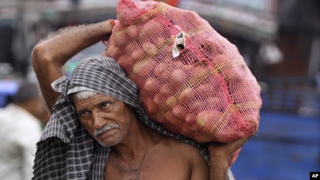 An Indian laborer carries a bag of potatoes at a warehouse in Jammu, India, July 31, 2012.