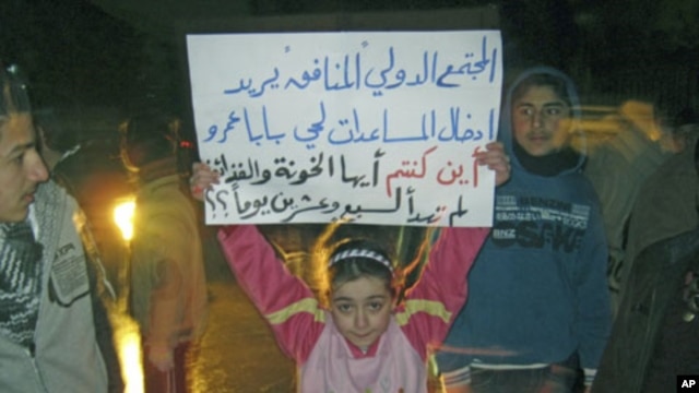 A girl whose father was killed during the recent shelling on Baba Amr district protests against Syria's President Bashar al-Assad in Al Qusour, Homs, March 3, 2012. The placard reads "The hypocritical international community wants to send aid to Baba Amr.