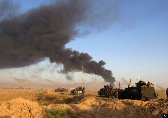 Smoke rises from Islamic State group positions after an airstrike by U.S.-led coalition warplanes in Fallujah, as Iraqi security forces and allied Shiite Popular Mobilization Forces and Sunni tribal fighters, take combat positions outside Fallujah, May 23
