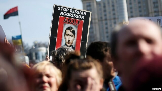 Người biểu tình cầm hình ảnh mô tả ông Putin như Adolf Hilter trong một cuộc biểu tình chống chiến tranh tại Kiev.