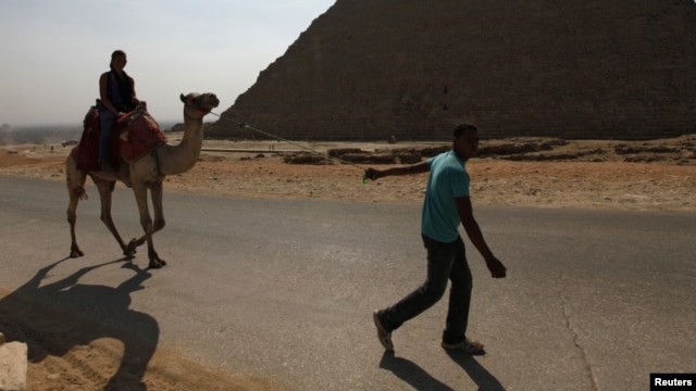 A man pulls a camel carrying a lone tourist at the Pyramids of Giza near Cairo October 19, 2011.