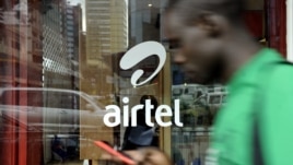 A man with his phone in hand walks past a window branded in an 'Airtel' logo on May 20, 2011 in the Kenyan capital, Nairobi. 