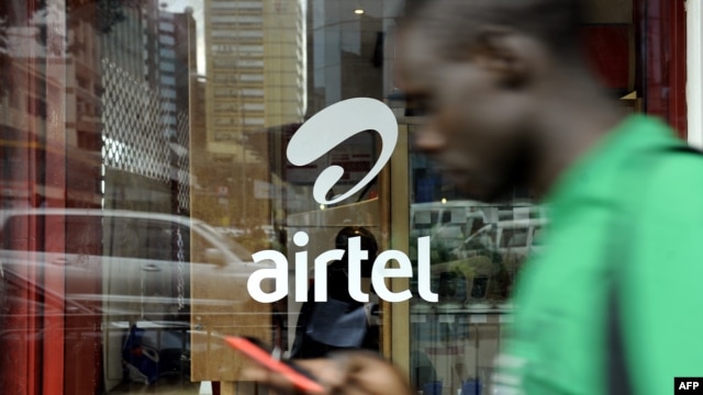 A man with his phone in hand walks past a window branded in an 'Airtel' logo on May 20, 2011 in the Kenyan capital, Nairobi. 