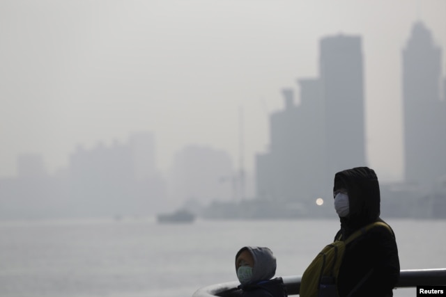 FILE - People wear protective masks near the Bund during a polluted day in Shanghai, China, Jan. 19, 2016.