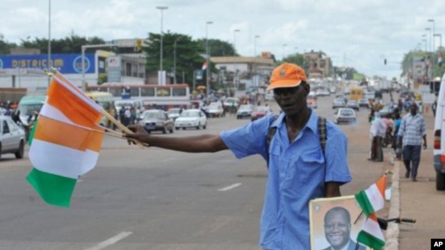 A street vendor sells Ivorian flags and portraits of Ivory Coast President Alassane Ouattara at a market in Yamoussoukro on May 20, 2011, before his investiture ceremony which is due to be held on May 21, 2011.
