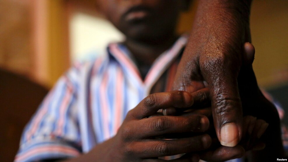 Nine-year-old Tumelo holds his grandmother's hand after taking his medication at Nkosi's Haven, south of Johannesburg November 28, 2014. Nkosi's Haven provides residential care for destitute HIV-positive mothers and their children, whether HIV-positive or