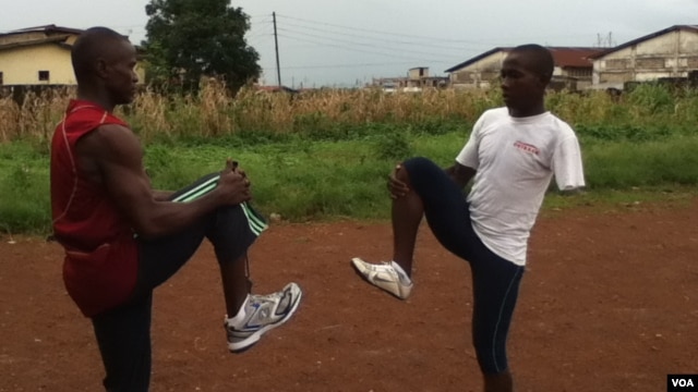 Mohamed Kamara and his coach, Abu Bakar Conteh, warm up before a training session ahead of the 2012 Paralympic. (VOA - N. deVries)