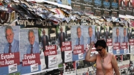 A woman walks past pre-election posters in Athens June 16, 2012. Greece holds general parliamentary elections on June 17. 