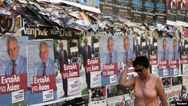 A woman walks past pre-election posters in Athens June 16, 2012. Greece holds general parliamentary elections on June 17. 