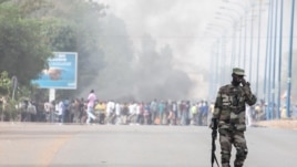 A soldier patrols near a burning road block outside the paratrooper camp, home of the former president's Red Beret presidential guard, in Bamako, February 8, 2013.