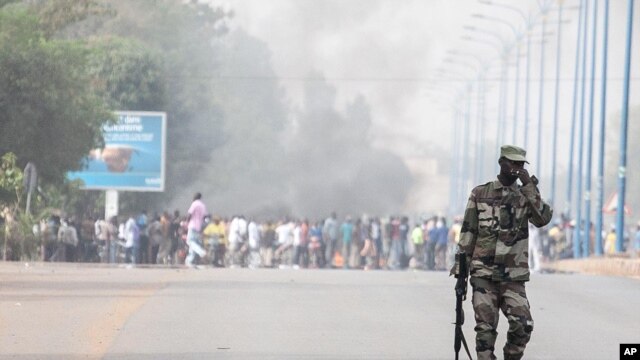 A soldier patrols near a burning road block outside the paratrooper camp, home of the former president's Red Beret presidential guard, in Bamako, February 8, 2013.