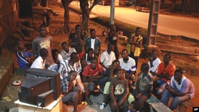 A group of young men watch the announcement of final provisional presidential election results shortly after midnight on the streets of a closed-up Bouake, in northern Ivory Coast, 04 Nov 2010