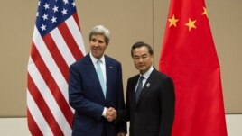 FILE - U.S. Secretary of State John Kerry, left, shakes hands with Chinese Foreign Minister Wang Yi as they pose for photos before their meeting at the 47th ASEAN Foreign Ministers' Meeting in Naypyitaw, Myanmar, Aug. 9,2014.