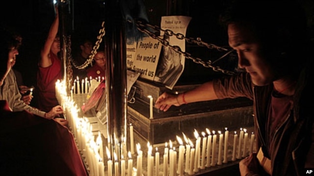 Exiled Tibetans light candles in front of portraits of 16-year-old monk Phuntsog, during a candlelit vigil to honor the monk who set himself on fire in an anti-government protest, in Dharmsala, India, March 16, 2011