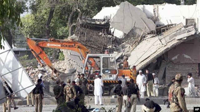 Pakistani soldiers, police officers check a police building after it was attacked by a suicide bomber in an explosives-laden pickup truck in Peshawar, Pakistan, May 25, 2011
