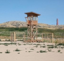 A replica of one of the camp’s watch towers in the exact place where it once stood. The smoke stack of the hospital is in the background.