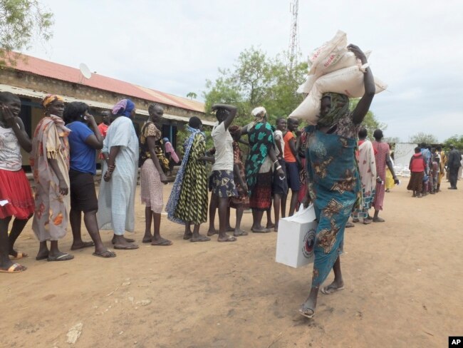 FILE - A South Sudanese woman carries food donated by Saudi Arabia Government through the Islamic Council of South Sudan in Juba, South Sudan, April 19, 2017.