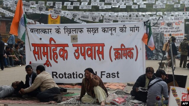 Protestors sits in front of a banner during a protest against last month's gang rape and murder of a student, in New Delhi, February 2, 2013.