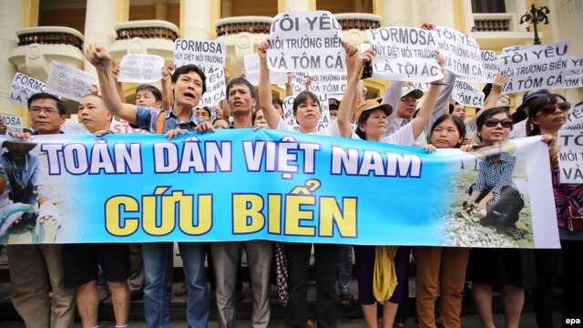 Người biểu tình ở Hà Nội cầm băng rôn và biểu ngữ phản đối vụ cá chết hàng loạt tại các tỉnh miền Trung, ngày 1/5/2016.