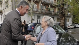 Montenegro’s ruling coalition of longtime leader Milo Djukanovic, left, talks to a supporter in front of the polling station in downtown Podgorica, Montenegro, Sunday, Oct. 14, 2012.