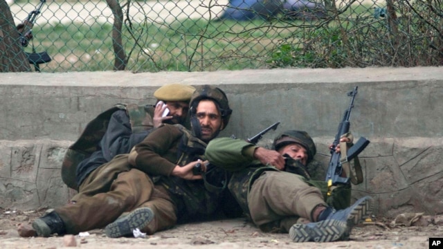 Indian police men take cover during a gun battle in Srinagar, India, Mar. 13, 2013.