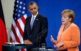 President Obama listens as German Chancellor Angela Merkel addresses the media during a press conference in Berlin, June 19, 2013.