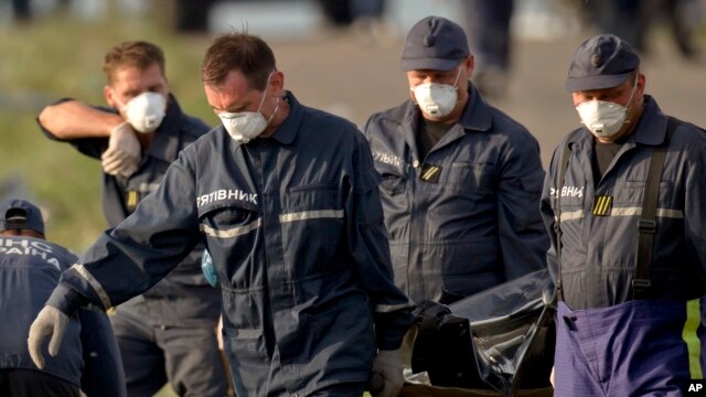 Nhân viên cấp cứu mang thi thể nạn nhân ra từ địa điểm tai nạn gần làng Hrabove, đông Ukraine.