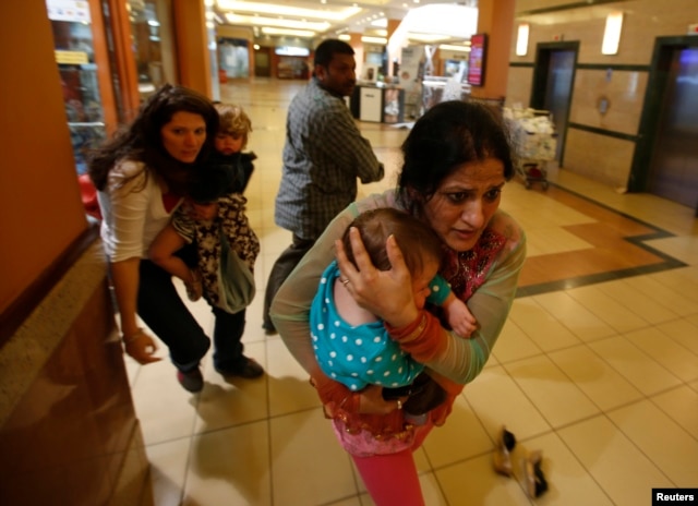 Women carrying children run for safety as armed police hunt gunmen who went on a shooting spree in Westgate shopping center in Nairobi, Sept. 21, 2013.