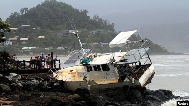 Warga mengamati sebuah perahu yang terhempas di pantai Airlie, sekitar 120 kilometer selatan-timur kota Townsville di Queensland, 25 Januari 2013. (REUTERS/Bon Fenney). Menurut keterangan pihak berwenang setempat, hujan lebat - sisa-sisa Badai Tropis Oswald - menyebabkan beberapa jalan raya utama dan puluhan jalan terputus, mengisolasi kota-kota dan menyebabkan banjir di berbagai tempat di Australia.
