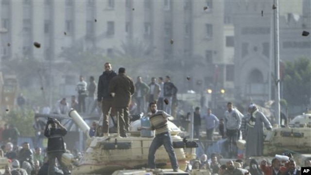 Supporters of President Hosni Mubarak, foreground , fight with anti-Mubarak protesters, rear, standing on army tanks in Cairo, February 2, 2011