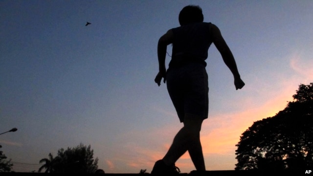 An exercise instructor is silhouetted against the dusk sky while leading a mass exercise routine at a park in Bangkok, Thailand. Every morning hundreds of health and sports enthusiasts gather in the park at the heart of the city's financial district where