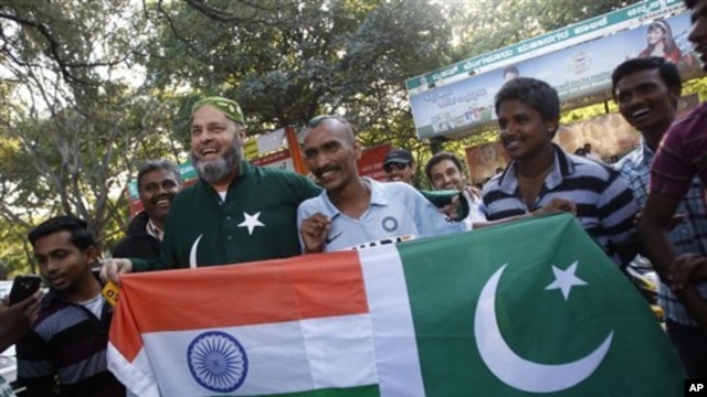 Mohammad Bashir (ketiga dari kiri), penggemar kriket dari Pakistan dan Sudhir Kumar (keempat dari kanan), warga India, membentangkan bendera India dan Pakistani yang dijahit jadi satu di depan stadion Chinnaswamy di Bangalore, India (25/12).