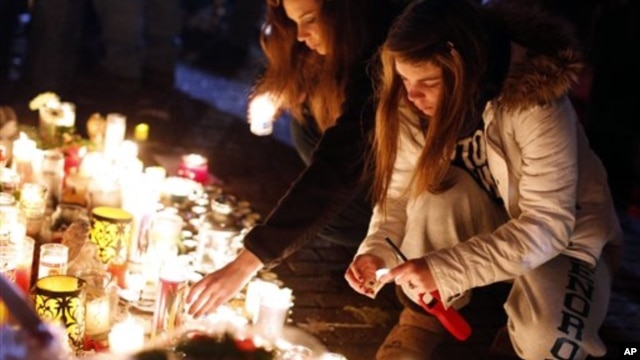 Visitors light candles at a memorial to shooting victims, Monday, Dec. 17, 2012, in Newtown, Conn. 