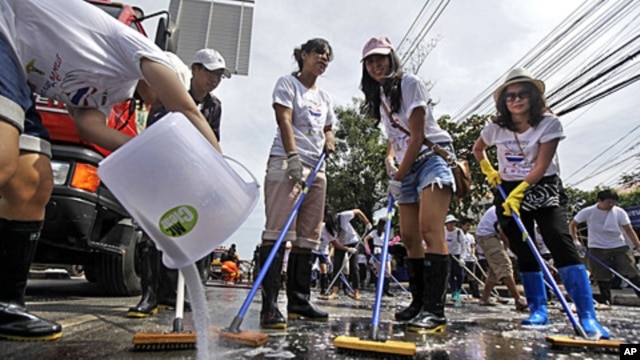 A Thai volunteer, left, pours detergent as others sweep a road during a cleaning drive after flood waters receded in Bangkok, Thailand, November 20, 2011.