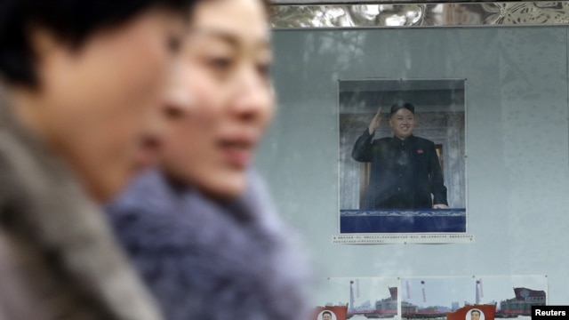 Women walk past a picture of the new North Korean leader Kim Jong-Un outside the North Korean Embassy in Beijing December 12, 2012.