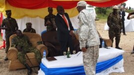 New president of the M23 rebel movement, Bertrand Bisimwa (in orange tie) shakes hands with M23 military commander Sultani Makenga, in Bunagana in eastern DRC, March 7, 2013. (N. Long/VOA)