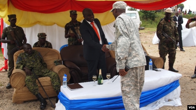 New president of the M23 rebel movement, Bertrand Bisimwa (in orange tie) shakes hands with M23 military commander Sultani Makenga, in Bunagana in eastern DRC, March 7, 2013. (N. Long/VOA)
