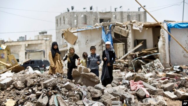 A boy and his sisters watch graffiti artists spray on a wall, commemorating the victims who were killed in Saudi-led coalition airstrikes in Sana'a, Yemen, May 18, 2015. 