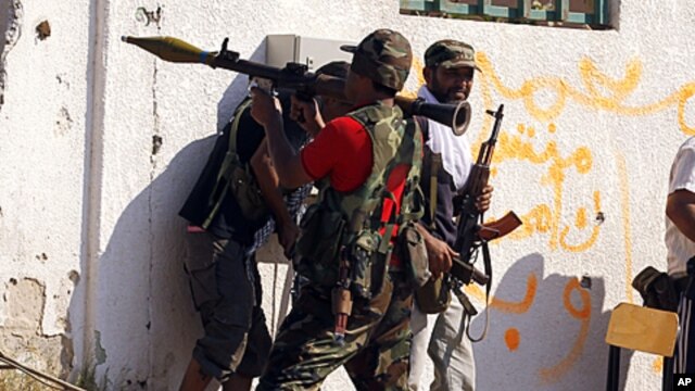 A Libyan rebel fighter prepares to fire a rocket propelled grenade launcher towards a sniper position as they make a final push to flush out pro-Gaddafi forces from the Bab al Aziziya compound in Tripoli, August 24, 2011