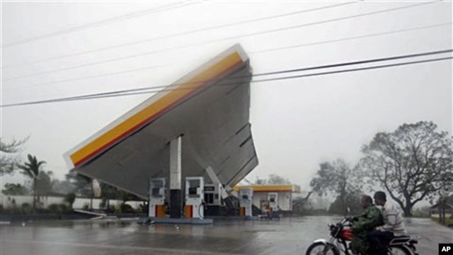 Motorists drive past a filling station which was toppled by typhoon Megi (local name "Juan"), 18 Oct 2010, at Cauayan, Isabela province, northeastern Philippines