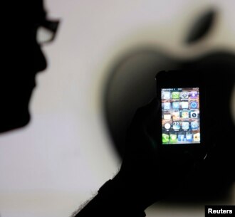 Seorang pria memegang ponsel iPhone 4 pada bayangan logo Apple di Zenica, Bosnia. (Foto: Dok)