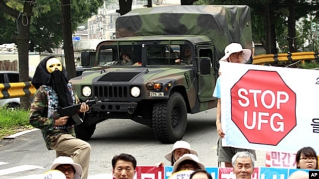 U.S. Army vehicle passes by South Korean protesters at a rally denouncing a South Korea-U.S. Combined Forces Command military exercise, in Seongnam, south of Seoul, South Korea, August 16, 2011