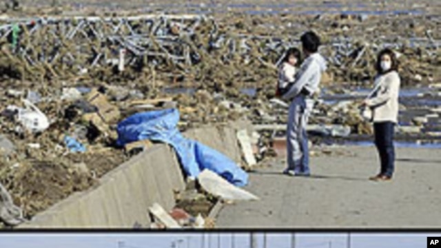 This combination of pictures shows local residents looking at a tsunami-hit area of Minamisoma, Fukushima Prefecture on March 12, 2011 (top) and the same area on January 11, 2012 (bottom).  